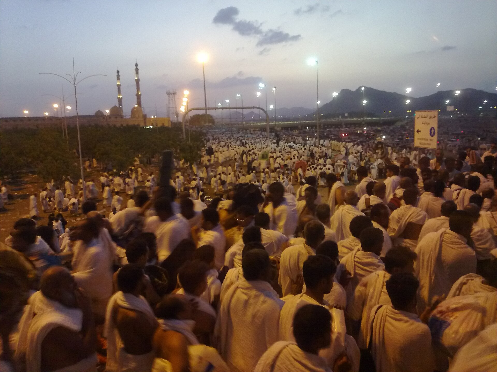 Pilgrims in ihram moving together through the crowds at dusk