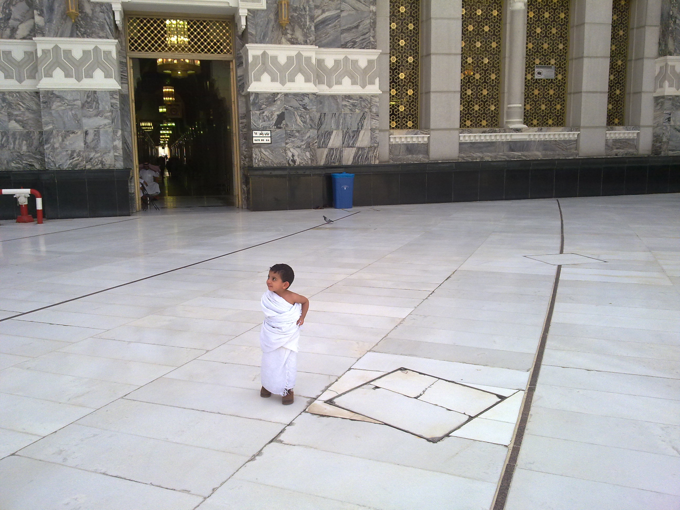 A young child in ihram standing in the courtyard of Masjid al-Haram